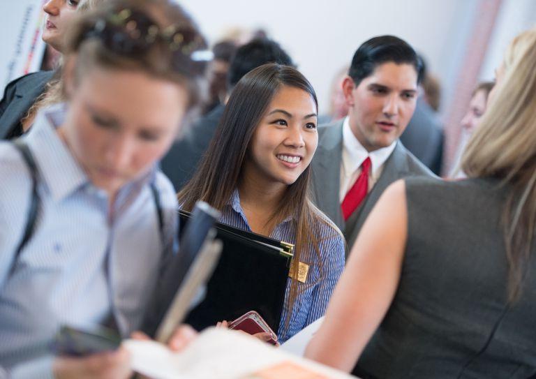 Graduate students meet with potential employers at a career resource center employer fair.